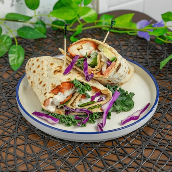 Two chicken wraps with red cabbage, lettuce, and white sauce on a white plate.