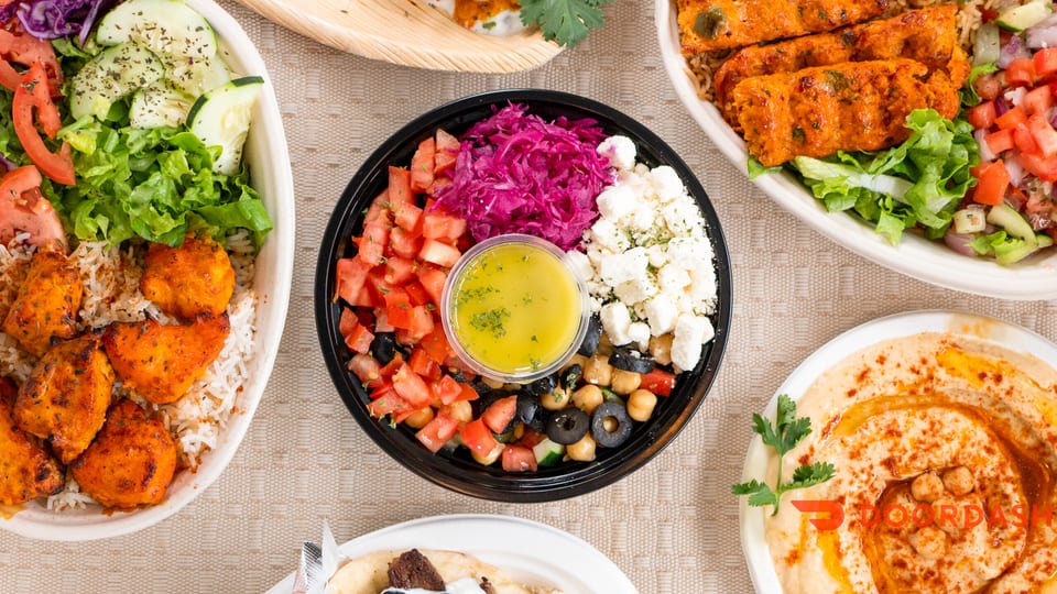Overhead view of various Mediterranean dishes, including chicken and rice bowls, a salad, and hummus.